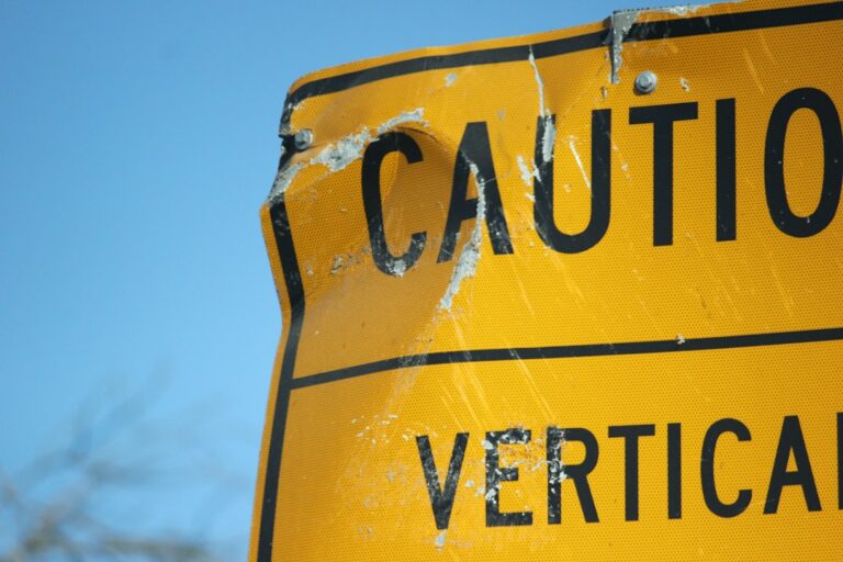 A close up of a street sign with a tree in the background