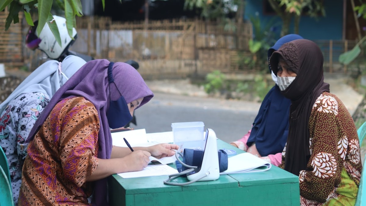 woman in brown and red hijab sitting on green box