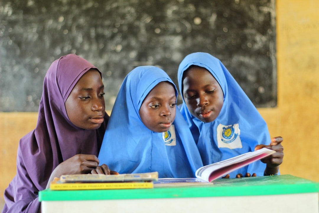a group of women in head scarves looking at a book