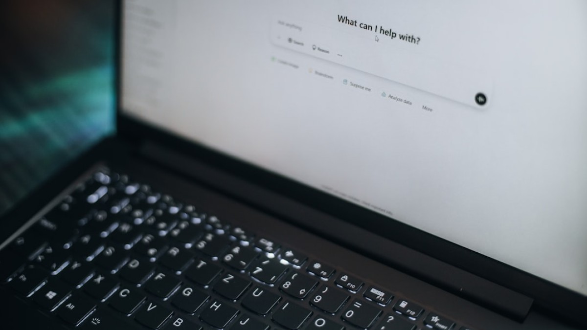 A laptop displays "what can i help with?"