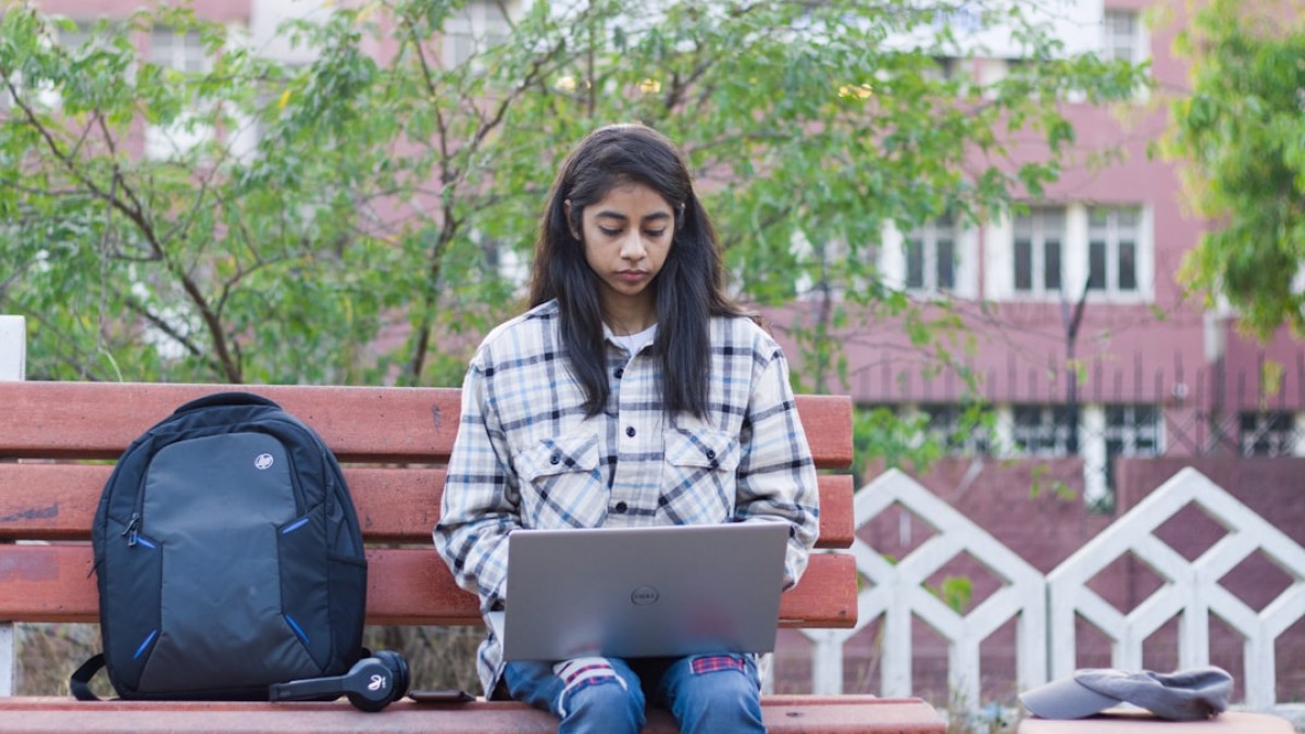 a woman sitting on a bench with a laptop
